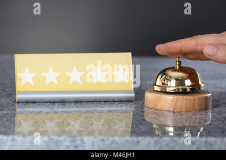 Close-up Of A Person Hand Ringing Service Bell Near Five Star Shape Card Stock Photo