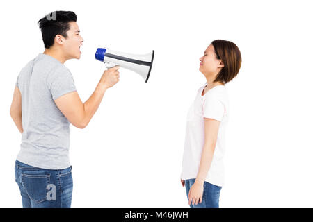 Angry man shouting at young woman on megaphone Stock Photo