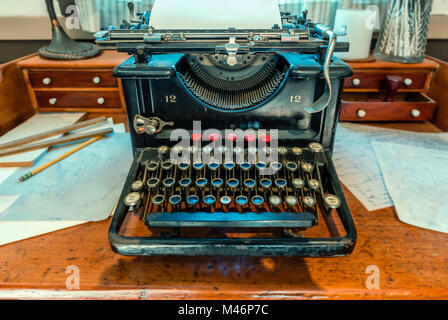 antique, typewriter with a sheet of white paper and a metal compass stands on a brown wooden table Stock Photo