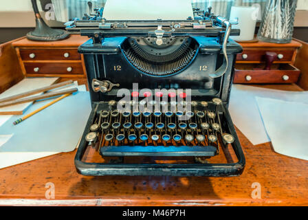 antique, typewriter with a sheet of white paper and a metal compass stands on a brown wooden table Stock Photo