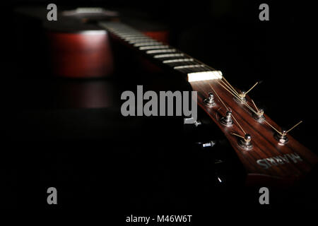 A shaded picture of a guitar. It lies in the dark with only a part visible under small amount of light. Stock Photo