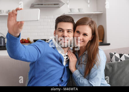 Young couple together at home weekend holding smartphone taking selfies Stock Photo