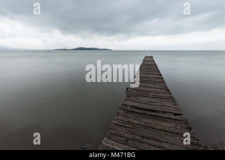 Long exposure first person view of a pier on a lake, with a tree Stock Photo