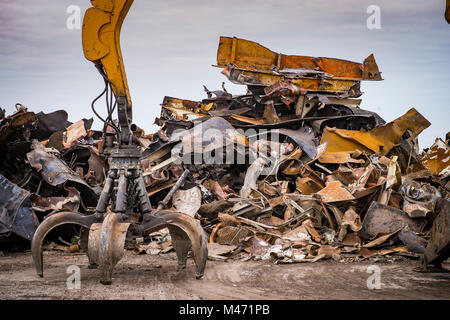 Large tracked excavator working a steel pile at a metal recycle yard, France Stock Photo