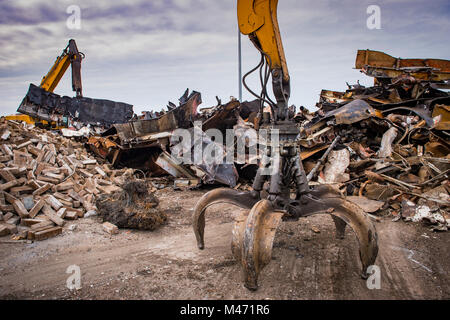 Large tracked excavator working a steel pile at a metal recycle yard, France Stock Photo