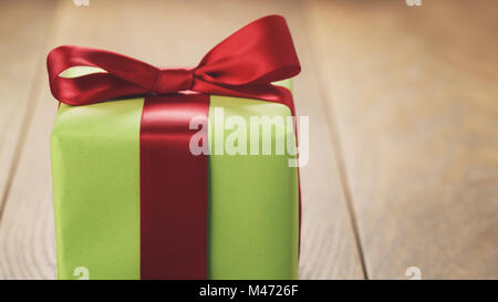 green paper gift box with classic red ribbon bow on wooden table Stock Photo