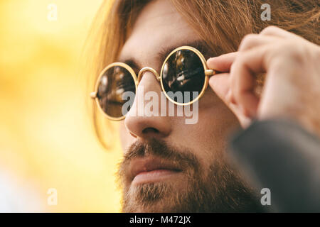 Close up portrait of a young bearded man wearing sunglasses outdoors Stock Photo