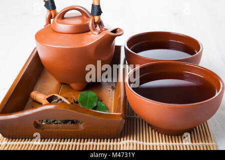 Ceramic teapot and tea leaves on a wooden tray. Oriental tea. Stock Photo