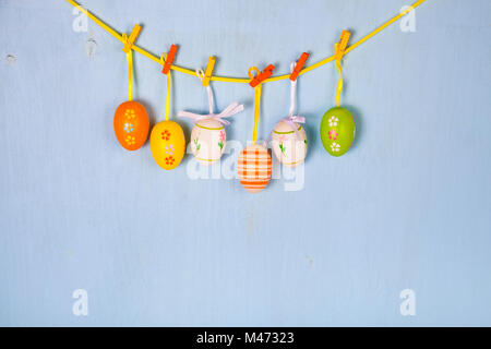 Easter Eggs on a rope on a blue wooden background.  Easter still life can be used as a postcard. Stock Photo