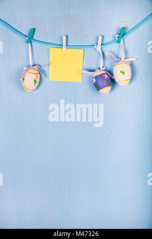 Easter Eggs and paper on a rope on a blue wooden background.  Easter still life can be used as a postcard. Stock Photo