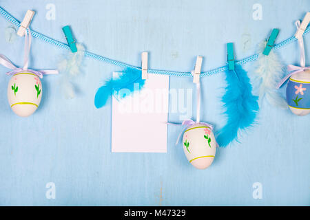 Easter Eggs and paper on a rope on a blue wooden background.  Easter still life can be used as a postcard. Stock Photo