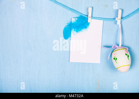 Easter Eggs and paper on a rope on a blue wooden background.  Easter still life can be used as a postcard. Stock Photo