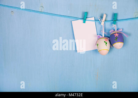Easter Eggs and paper on a rope on a blue wooden background.  Easter still life can be used as a postcard. Stock Photo