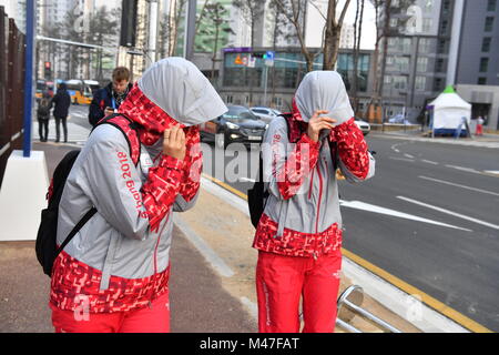 Gangneung, South Korea. 14th Feb, 2018. Volunteers fighting against the strong wind in Gangneung, South Korea, 14 February 2018. Credit: Peter Kneffel/dpa/Alamy Live News Stock Photo