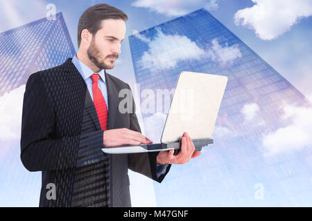 Composite image of focused businessman using his laptop Stock Photo