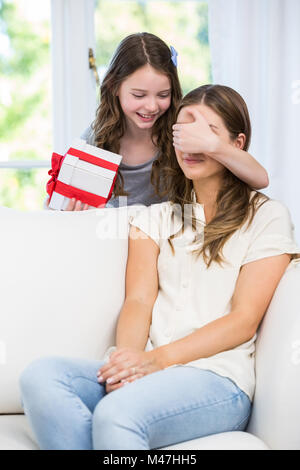 Daughter covering eyes of mother for surprise gift Stock Photo