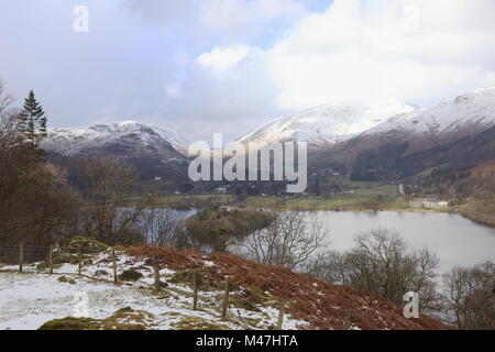 Grasmere, Cumbria, in mid winter, bright sunlight reflects off the snow covered Helvelyn range. Stock Photo