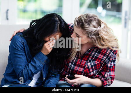 Young woman consoling crying female friend at home Stock Photo