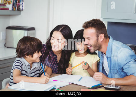 Cheerful parents assisting children in homework Stock Photo