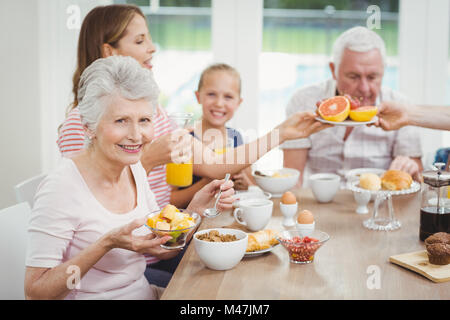 Happy multi-generation family eating fruits during breakfast Stock Photo