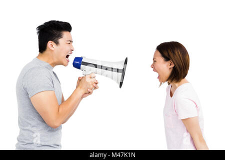 Angry man shouting at young woman on megaphone Stock Photo