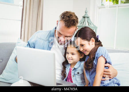 Father and daughters looking in laptop at home Stock Photo