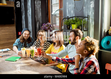 Friends clinking glasses in the modern cafe Stock Photo