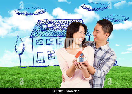 Composite image of cheerful couple holding a model house Stock Photo