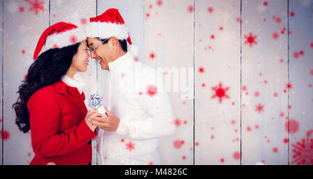 Composite image of festive senior couple exchanging gifts Stock Photo