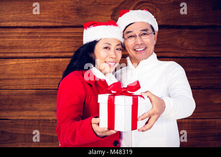 Composite image of festive senior couple exchanging gifts Stock Photo