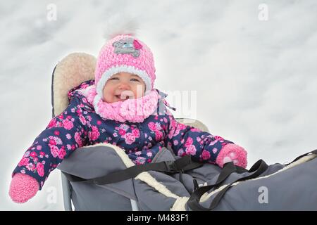 Cute little girl sitting on her sledge in winter day Stock Photo