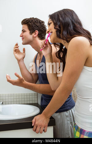 Couple in bathroom applying cream and brushing teeth Stock Photo