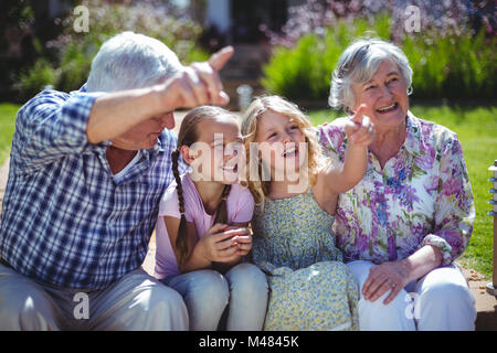 Cheerful girls with grandparents while sitting in back yard Stock Photo