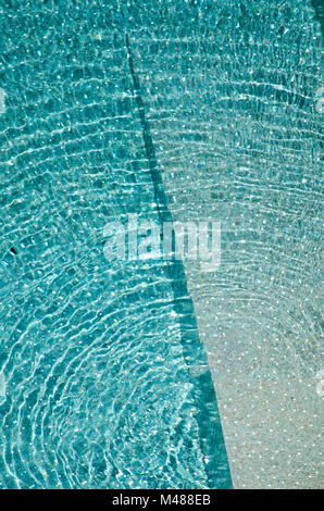 abstract portrait background of ripples or waves on water in swimming pool; shades of blue or turquoise glass tiles on sunny relaxing day in summer Stock Photo