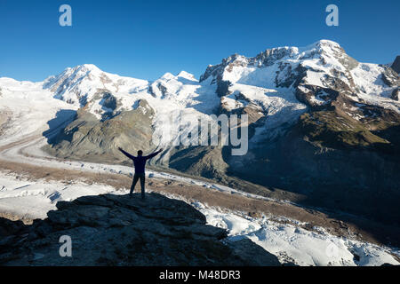 Hiker silhouetted beside Gorner Glacier and Monte Rosa, Gornergrat, Zermatt, Switzerland. Stock Photo