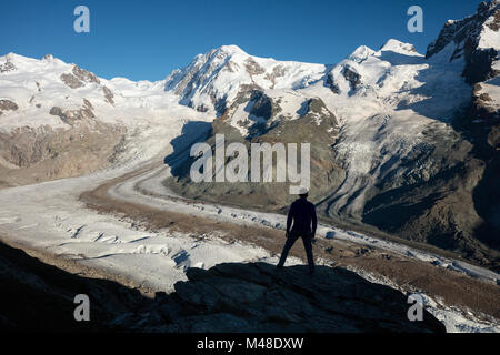 Hiker silhouetted beside Gorner Glacier and Monte Rosa, Gornergrat, Zermatt, Switzerland. Stock Photo