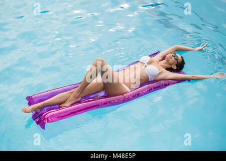 Beautiful young woman relaxing on inflatable raft Stock Photo