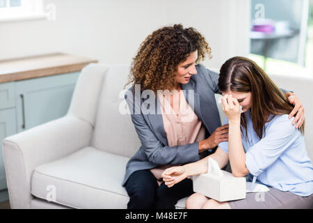 Psychologist consoling depressed woman at home Stock Photo