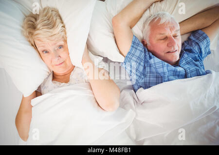 Portrait of woman covering ears from snoring husband Stock Photo