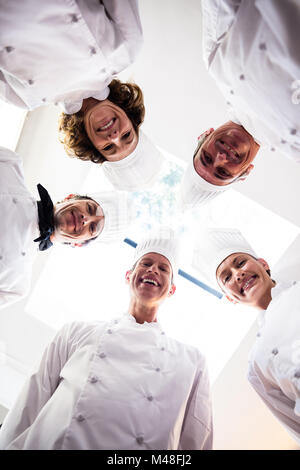 Portrait of chefs team standing in a circle wearing uniforms Stock Photo