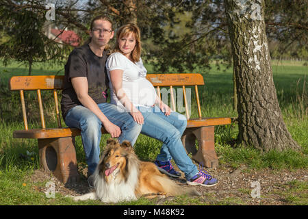 Happy family sitting on a bench in spring nature Stock Photo