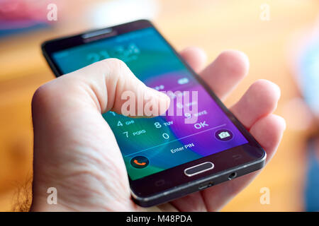 BUENOS AIRES, ARGENTINA - FEBRUARY 15, 2018: A person holding a mobile phone and entering the security code (PIN) to unlock it. Focus on "Enter PIN". Stock Photo