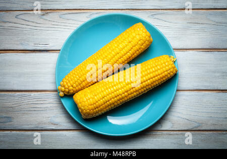 boiled corn on blue plate on white wooden background Stock Photo