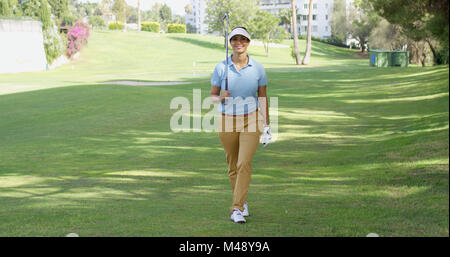 Smiling friendly woman golfer walking on a course Stock Photo