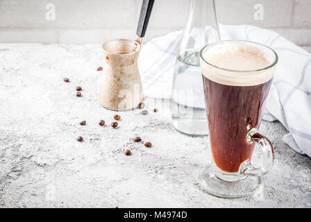 Trendy modern drink. Coffee espresso with mineral water, with coffee maker and roasted beans, Gray stone background, copy space Stock Photo