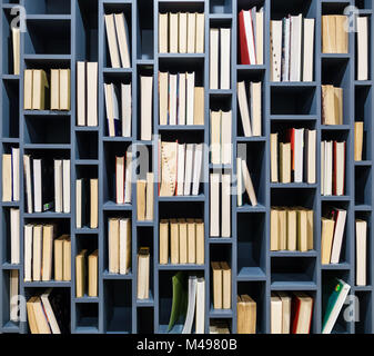 Books on blue wooden bookshelf. Book fore edges facing the front. Stock Photo