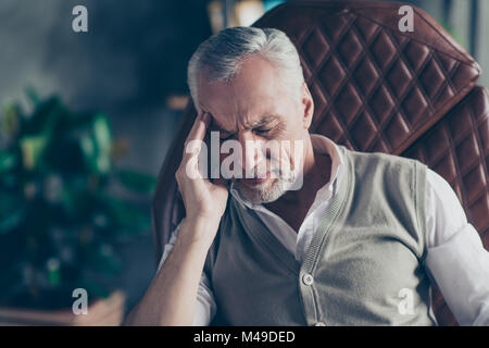 Close up portrait of sad upset nervous troubled problematic entrepreneur having strong headache wearing knitted waistcoat white shirt touching head te Stock Photo