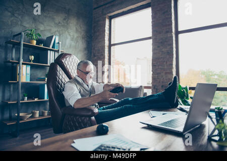 Yes I am winner! Side profile view photo of cheerful excited glad delightful restless careless freelancer playing game sitting on chair wearing jeans  Stock Photo