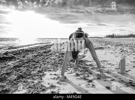 Refreshing wild sea side workout. active sportswoman in sports gear on the beach workout Stock Photo