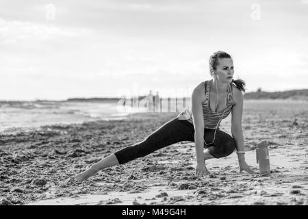 Refreshing wild sea side workout. healthy fit woman in sports gear on the seacoast stretching Stock Photo